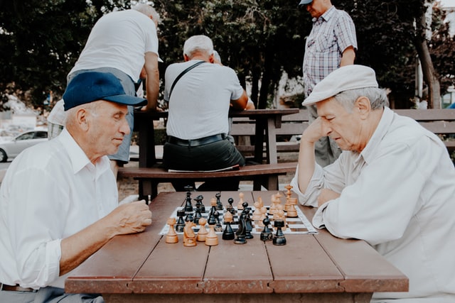 two senior men playing chess in the park